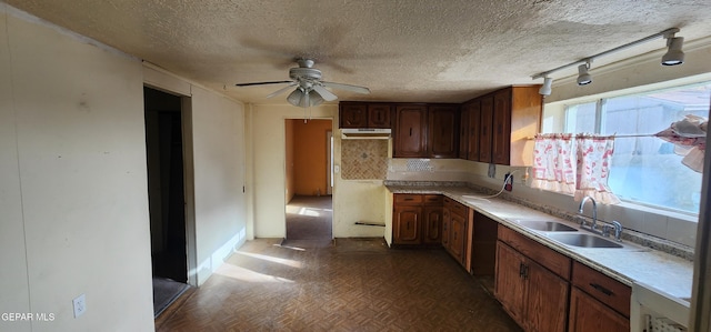 kitchen with a ceiling fan, a sink, decorative backsplash, light countertops, and a textured ceiling