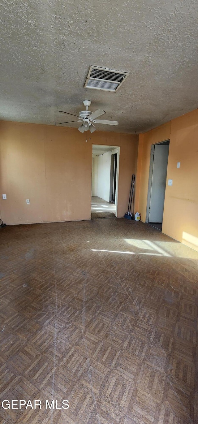 empty room featuring a ceiling fan, visible vents, and a textured ceiling