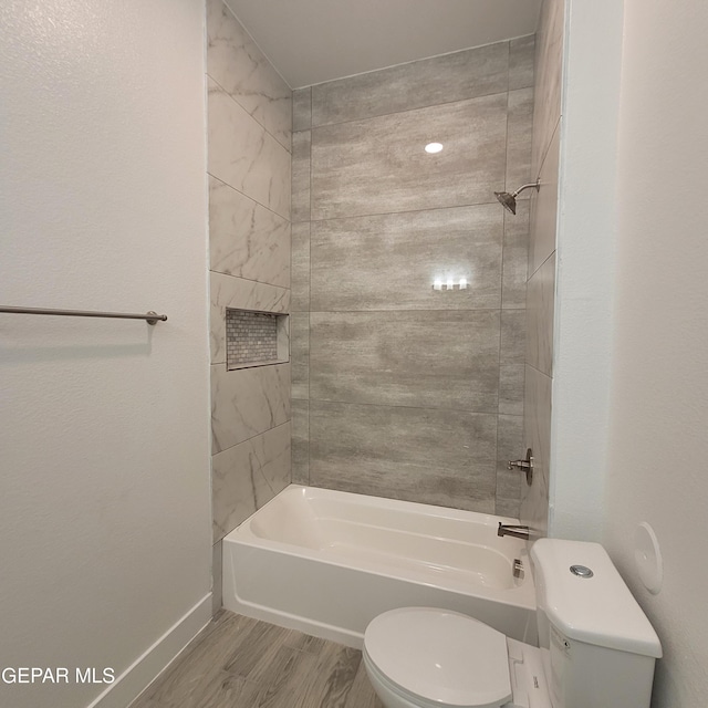 bathroom featuring tiled shower / bath combo, hardwood / wood-style flooring, and toilet