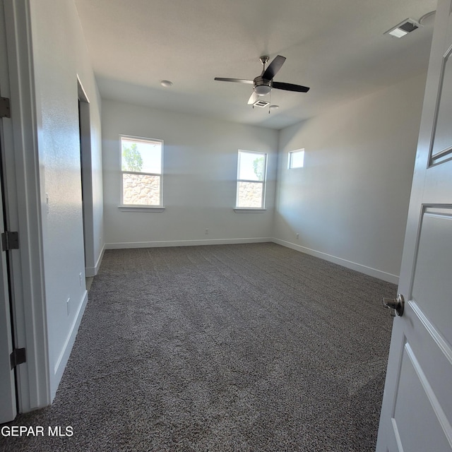 empty room featuring dark colored carpet and ceiling fan