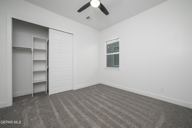 unfurnished bedroom featuring ceiling fan, dark carpet, and a closet