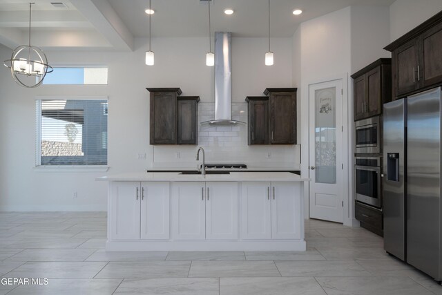 kitchen with a notable chandelier, decorative light fixtures, wall chimney range hood, and appliances with stainless steel finishes