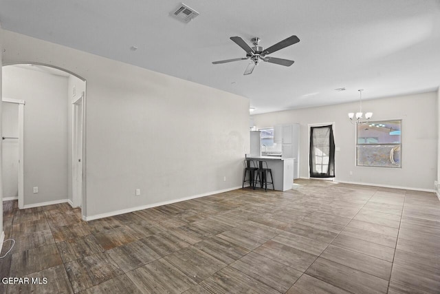 unfurnished living room with ceiling fan with notable chandelier