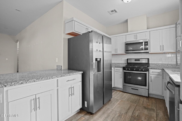 kitchen featuring white cabinetry, stainless steel appliances, tasteful backsplash, and hardwood / wood-style flooring