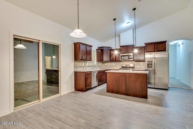 kitchen with appliances with stainless steel finishes, a center island, high vaulted ceiling, tasteful backsplash, and pendant lighting