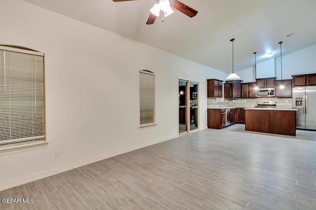 kitchen featuring ceiling fan, a center island, backsplash, decorative light fixtures, and stainless steel appliances