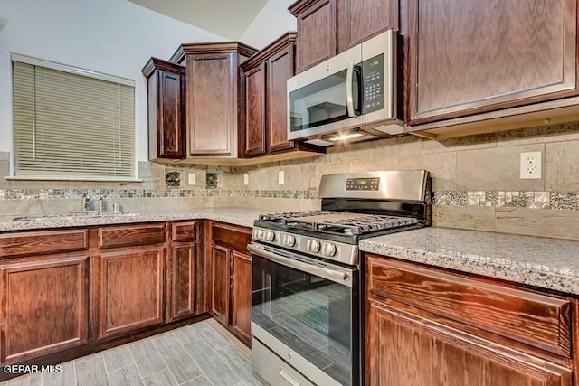 kitchen with sink, tasteful backsplash, stainless steel appliances, and light stone countertops