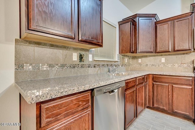 kitchen featuring stainless steel dishwasher, sink, tasteful backsplash, and light stone countertops