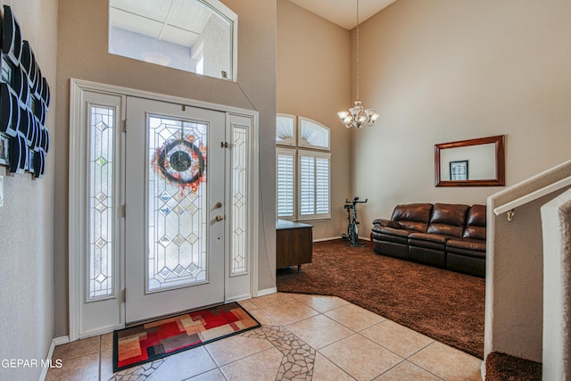 carpeted foyer entrance featuring a high ceiling, a wealth of natural light, and an inviting chandelier