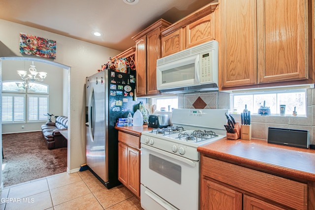 kitchen featuring light carpet, white appliances, tasteful backsplash, and an inviting chandelier