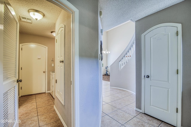 corridor featuring a textured ceiling and light tile floors