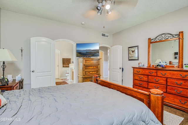 carpeted bedroom with ensuite bath, ceiling fan, and a textured ceiling