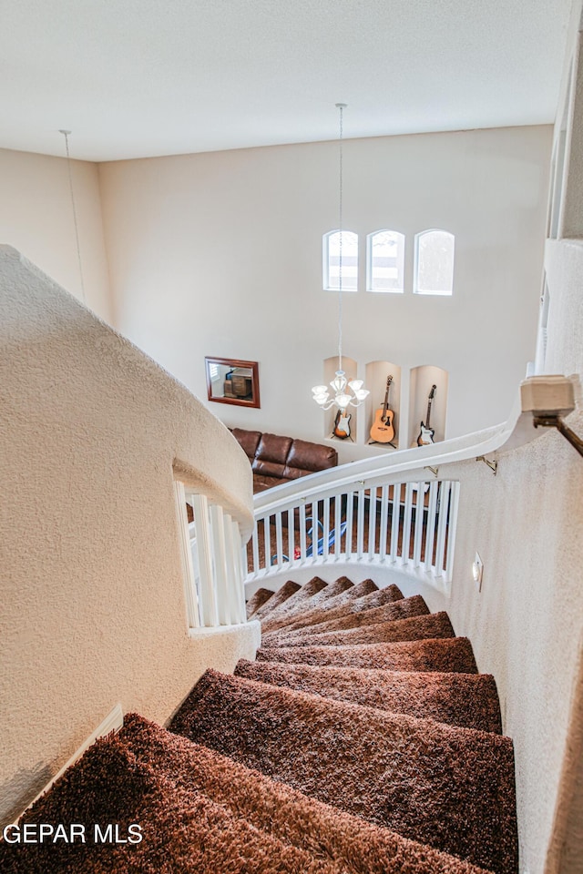 stairs featuring a towering ceiling and an inviting chandelier