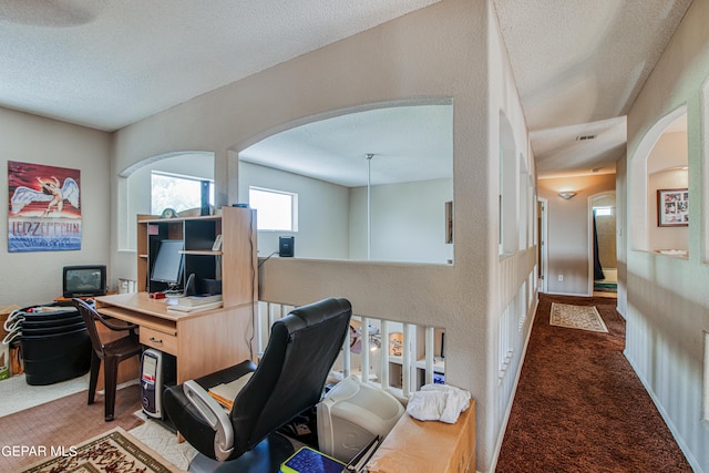 carpeted office featuring a textured ceiling