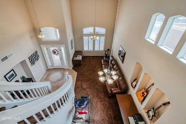 carpeted living room with a towering ceiling and an inviting chandelier