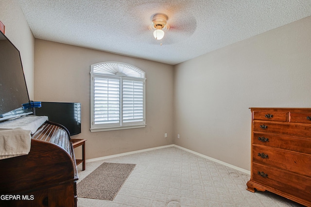 bedroom with light carpet, ceiling fan, and a textured ceiling