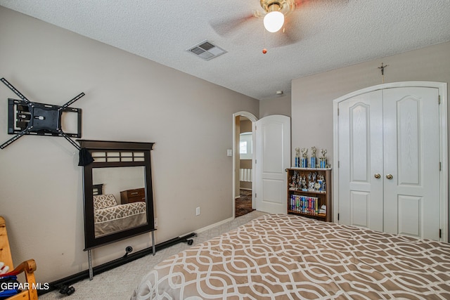 bedroom featuring a closet, ceiling fan, carpet floors, and a textured ceiling