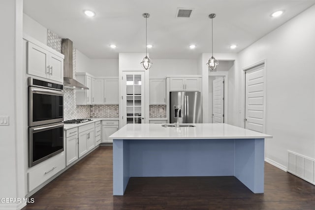 kitchen with a center island with sink, appliances with stainless steel finishes, tasteful backsplash, and dark hardwood / wood-style floors