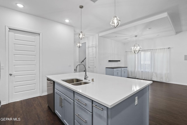 kitchen featuring hanging light fixtures, gray cabinets, an island with sink, sink, and dark hardwood / wood-style flooring