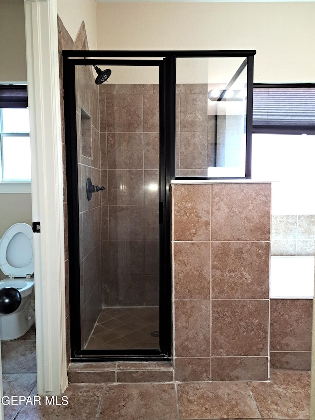 bathroom with tile flooring, a shower with shower door, and toilet