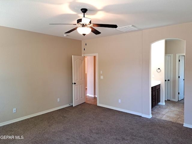 interior space featuring ceiling fan, connected bathroom, and light colored carpet