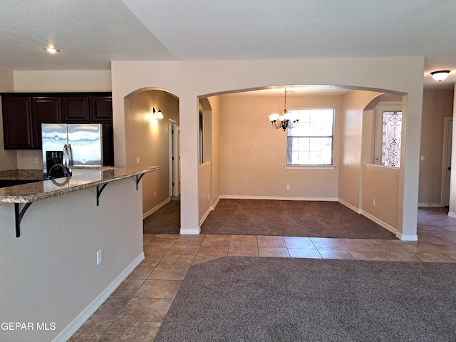 kitchen featuring dark brown cabinets, light carpet, hanging light fixtures, a breakfast bar area, and stainless steel fridge with ice dispenser