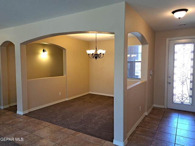 entrance foyer featuring carpet and a chandelier