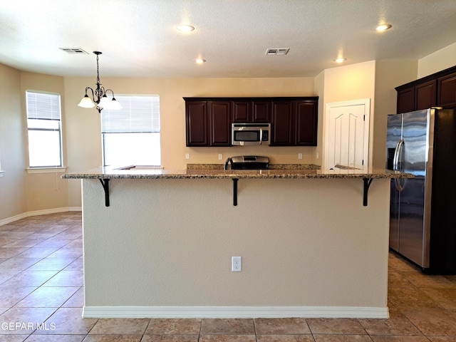 kitchen with a kitchen breakfast bar, appliances with stainless steel finishes, and light tile floors