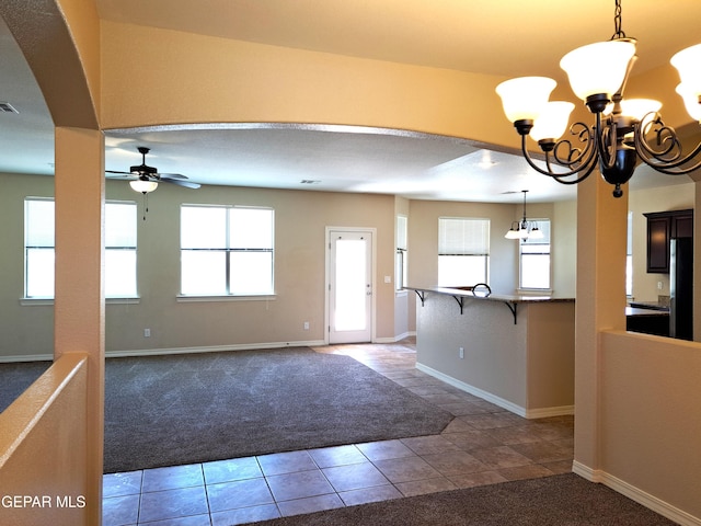 foyer entrance with ceiling fan with notable chandelier, a healthy amount of sunlight, and carpet floors