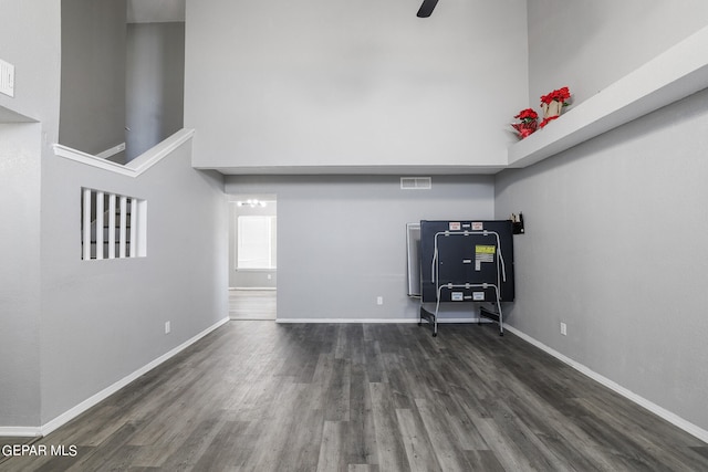 unfurnished office featuring a towering ceiling and dark hardwood / wood-style floors