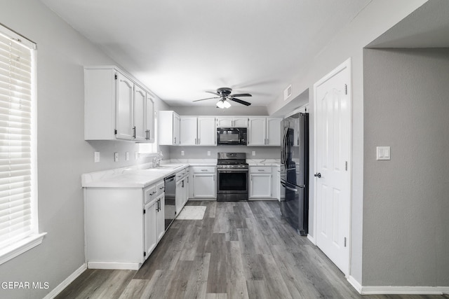 kitchen featuring plenty of natural light, white cabinetry, black appliances, hardwood / wood-style flooring, and ceiling fan