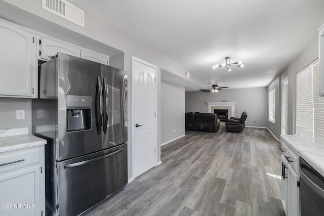 kitchen with appliances with stainless steel finishes, ceiling fan, white cabinets, light hardwood / wood-style flooring, and light stone countertops