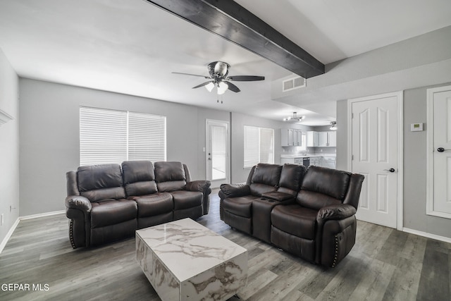 living room featuring wood-type flooring, ceiling fan, and beamed ceiling