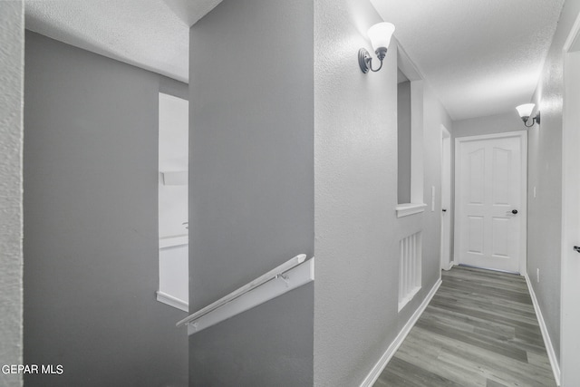 hall featuring wood-type flooring and a textured ceiling