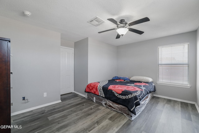 bedroom with dark hardwood / wood-style floors, ceiling fan, and a textured ceiling