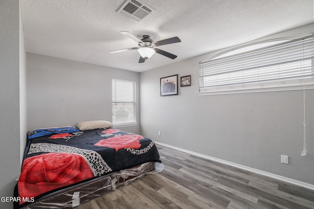 bedroom with ceiling fan, dark hardwood / wood-style floors, and a textured ceiling