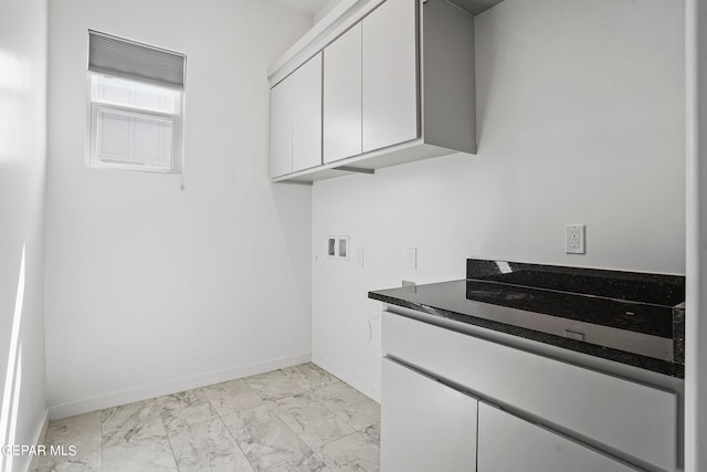 washroom with light tile flooring, cabinets, and hookup for a washing machine