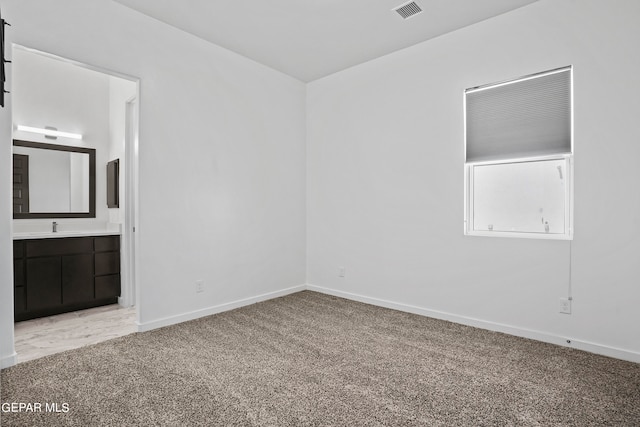 interior space featuring carpet flooring, ensuite bath, and sink