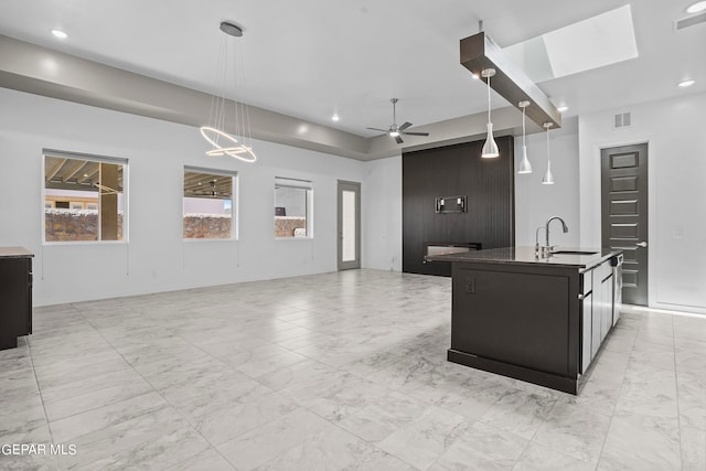 kitchen featuring hanging light fixtures, sink, light tile floors, and an island with sink