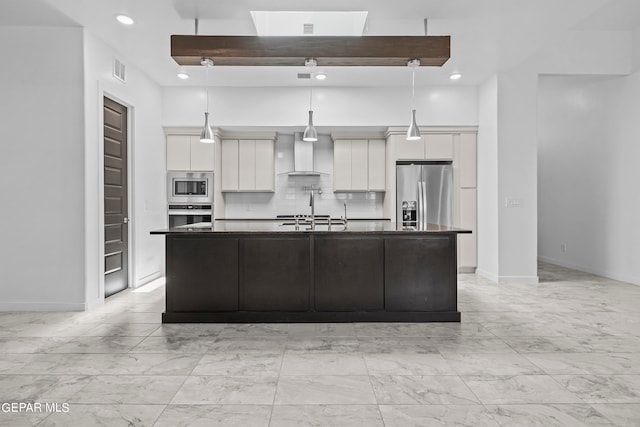 kitchen featuring a kitchen island with sink, decorative light fixtures, wall chimney range hood, stainless steel appliances, and sink