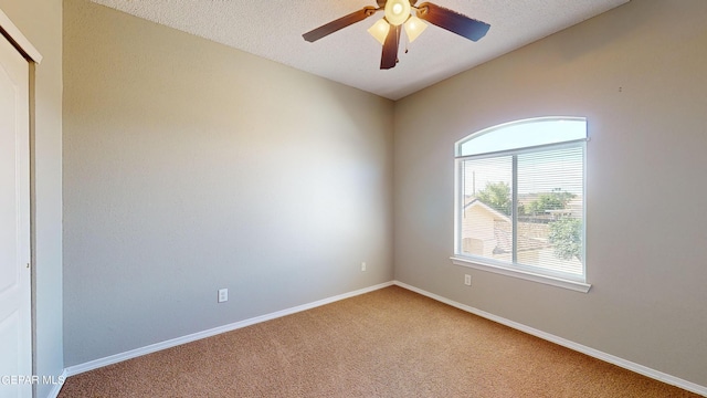 carpeted spare room with a textured ceiling and ceiling fan