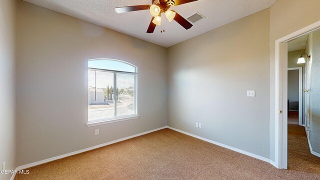 spare room featuring a textured ceiling, ceiling fan, and carpet floors