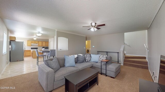 tiled living room featuring a textured ceiling, washer / dryer, and ceiling fan