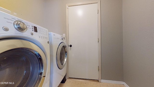 clothes washing area with washing machine and clothes dryer and light tile flooring