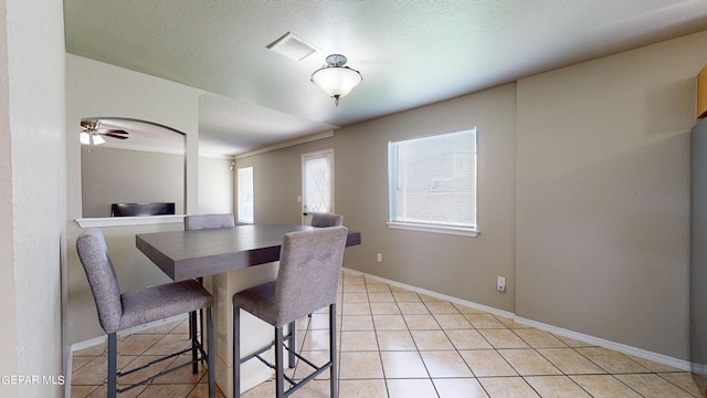 dining space with ceiling fan, a textured ceiling, and light tile floors