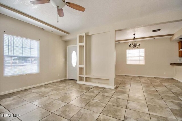 interior space featuring ceiling fan with notable chandelier, a healthy amount of sunlight, and light tile flooring