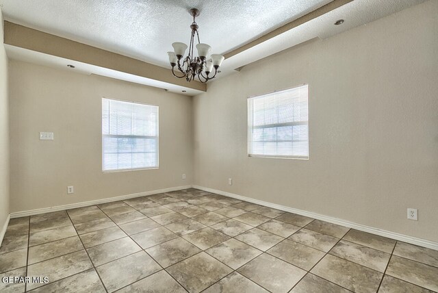 spare room with a chandelier, tile flooring, and a textured ceiling