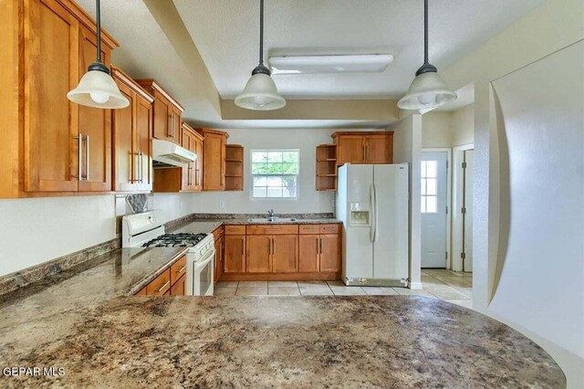 kitchen with hanging light fixtures, light tile flooring, white appliances, and dark stone countertops