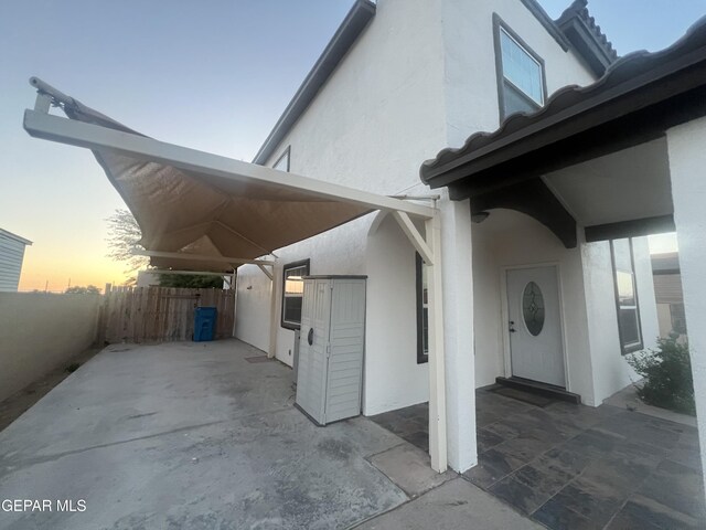 property exterior at dusk featuring a patio area