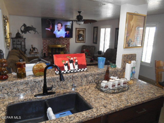 kitchen featuring a wealth of natural light, a brick fireplace, sink, and ceiling fan